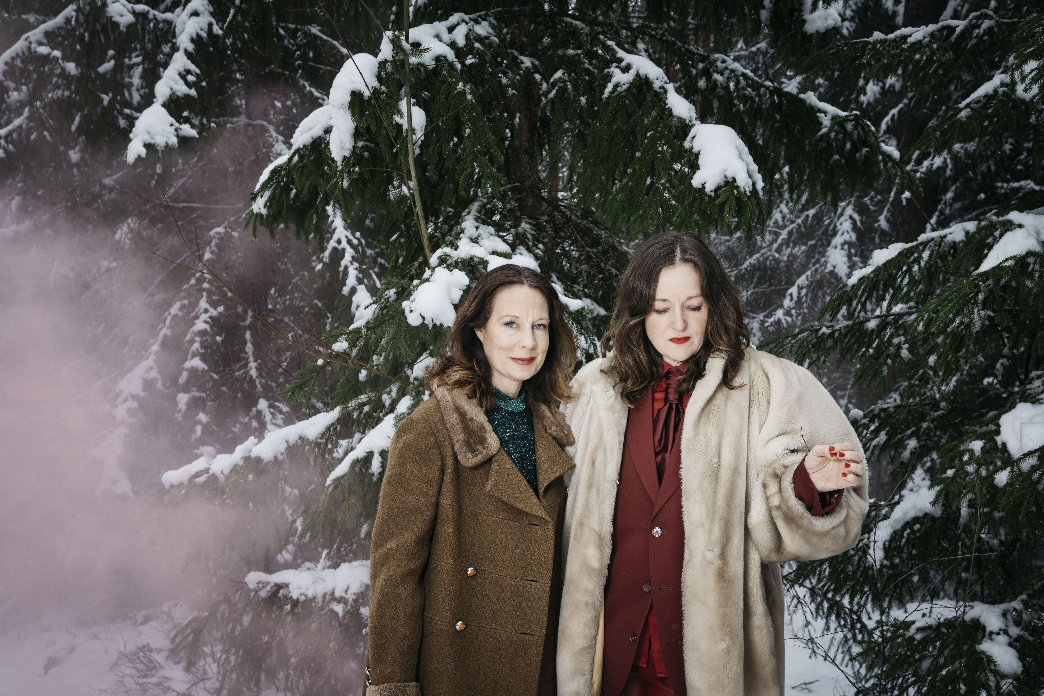 Musikerna i YoJuliet, två mörkhåriga kvinnor, står i en vintrig skog.